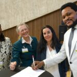 Four members of Research4Life posing whilst signing a document.