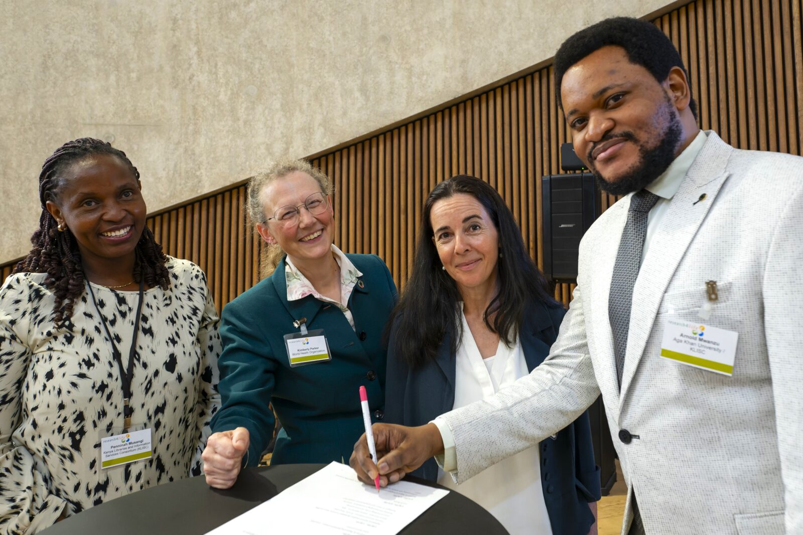 Four members of Research4Life posing whilst signing a document.
